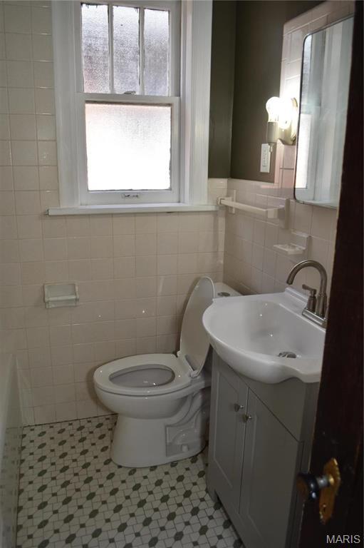 4521 Tholozan Ave, Saint Louis, MO 63116 - bathroom with tile walls, vanity, tile patterned floors, and a tub to relax in
