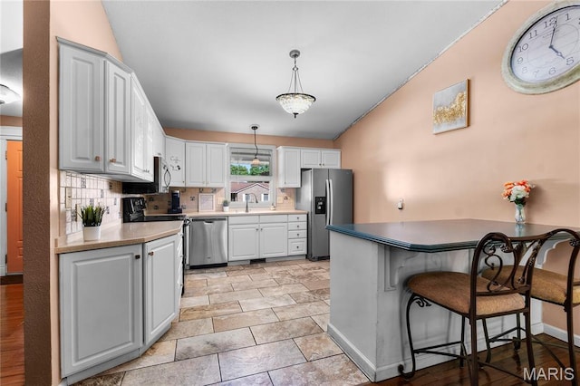 1133 Cypress Ct, Cape Girardeau, MO 63701 - kitchen featuring appliances with stainless steel finishes, lofted ceiling, a peninsula, decorative backsplash, and pendant lighting