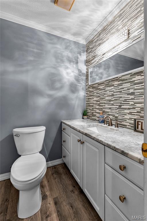 1133 Cypress Ct, Cape Girardeau, MO 63701 - half bathroom with vanity, wood finished floors, decorative backsplash, and crown molding