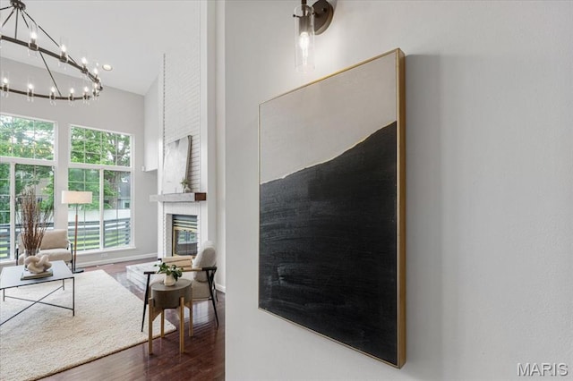 938 Blase Ave, Saint Louis, MO 63131 - living area featuring wood finished floors, a chandelier, a towering ceiling, and a large fireplace