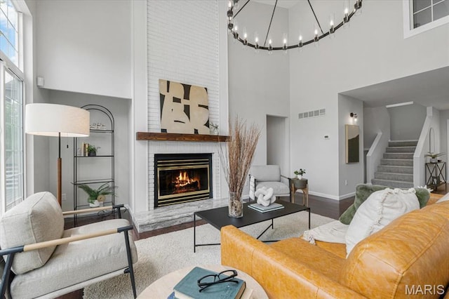 938 Blase Ave, Saint Louis, MO 63131 - living room featuring a towering ceiling, wood finished floors, stairway, a brick fireplace, and a chandelier
