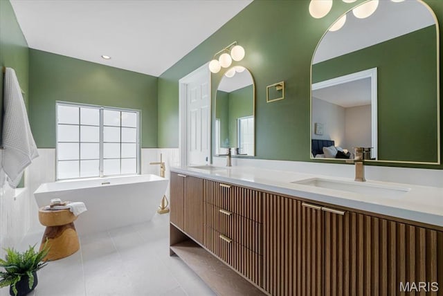 938 Blase Ave, Saint Louis, MO 63131 - full bath with double vanity, a freestanding tub, tile patterned floors, and wainscoting