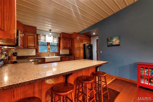 1369 County Highway 408, Benton, MO 63736 - kitchen with freestanding refrigerator, a peninsula, stainless steel microwave, a kitchen bar, and brown cabinets