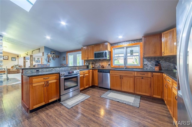 317 Johnson Pl, Palmyra, MO 63461 - kitchen featuring appliances with stainless steel finishes, a peninsula, dark wood finished floors, tasteful backsplash, and vaulted ceiling