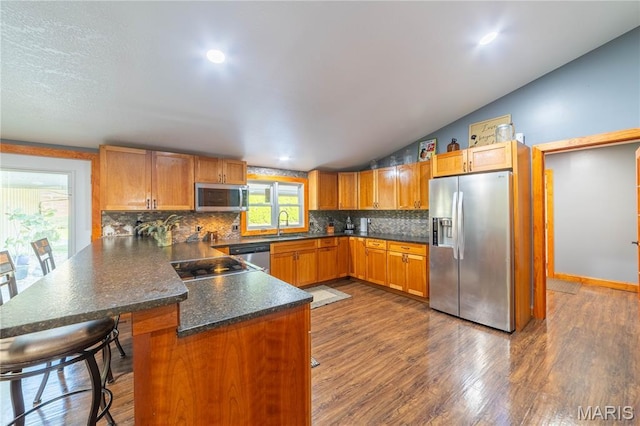 317 Johnson Pl, Palmyra, MO 63461 - kitchen with appliances with stainless steel finishes, a peninsula, decorative backsplash, vaulted ceiling, and dark countertops
