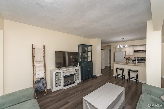 6451 Odell St, Saint Louis, MO 63139 - living room with a chandelier, dark wood-style floors, a textured ceiling, and a fireplace