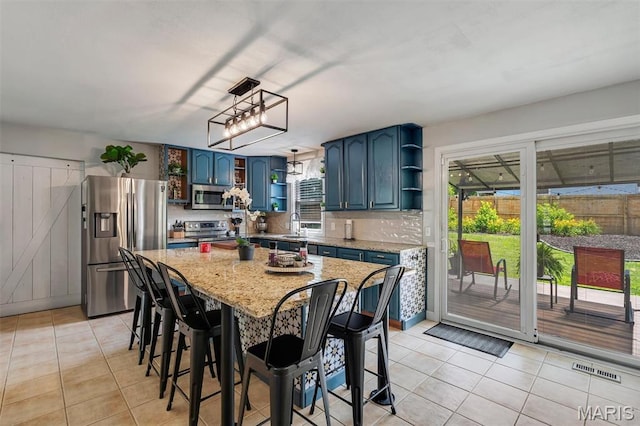 308 Rebecca Dr, Saint Charles, MO 63301 - kitchen with open shelves, appliances with stainless steel finishes, light tile patterned flooring, blue cabinets, and healthy amount of natural light