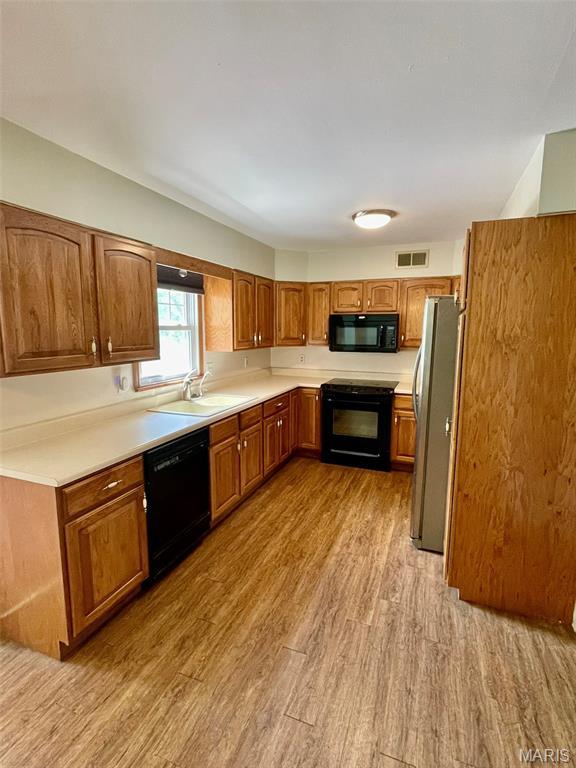 12 Dee, Moro, IL 62067 - kitchen featuring black appliances, wood finished floors, brown cabinets, and light countertops