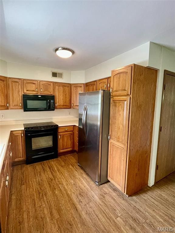 12 Dee, Moro, IL 62067 - kitchen with black appliances, wood finished floors, light countertops, and brown cabinetry