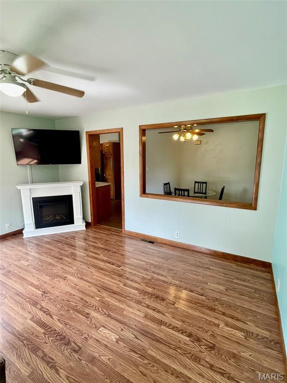 12 Dee, Moro, IL 62067 - unfurnished living room featuring ceiling fan, wood finished floors, and a fireplace