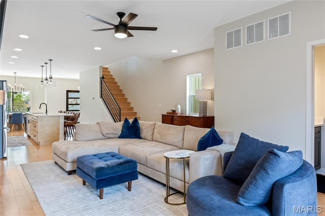 6297 Magnolia Ave, Saint Louis, MO 63139 - living room featuring stairs, light wood-type flooring, recessed lighting, ceiling fan, and a chandelier