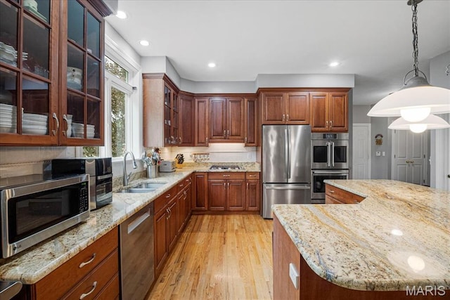 2175 Oberhelman Rd, Foristell, MO 63348 - kitchen featuring appliances with stainless steel finishes, light wood-style floors, light stone countertops, pendant lighting, and glass insert cabinets