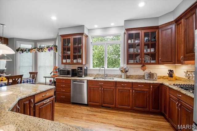 2175 Oberhelman Rd, Foristell, MO 63348 - kitchen with appliances with stainless steel finishes, light wood-type flooring, light stone counters, hanging light fixtures, and glass insert cabinets
