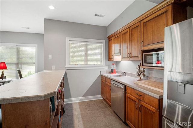 2175 Oberhelman Rd, Foristell, MO 63348 - kitchen featuring stainless steel appliances, a peninsula, brown cabinetry, light countertops, and healthy amount of natural light