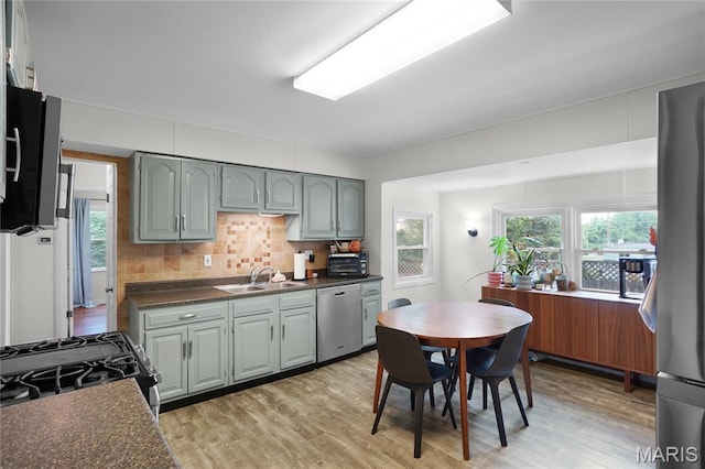 10502 Kamping Ln, Saint Louis, MO 63123 - kitchen with stainless steel dishwasher, gas stove, gray cabinetry, dark countertops, and light wood-style flooring