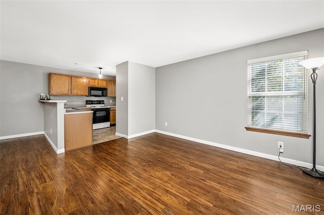1141 Arbor Creek Dr Unit 2C, Saint Louis, MO 63122 - kitchen featuring white electric range oven, black microwave, brown cabinetry, dark wood-style floors, and a peninsula