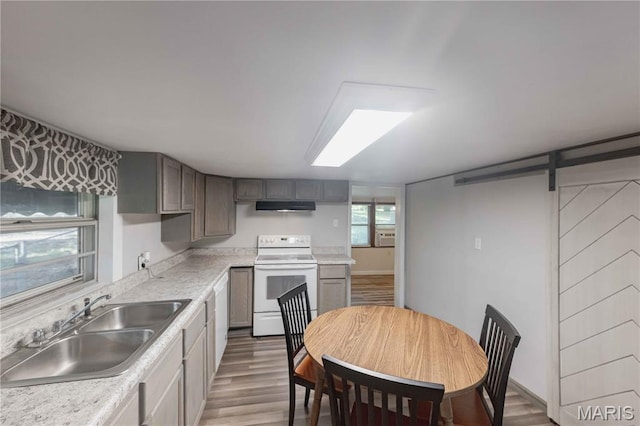 656 Sunset Farms Trl, Union, MO 63084 - kitchen with white electric stove, under cabinet range hood, a barn door, wood finished floors, and light countertops