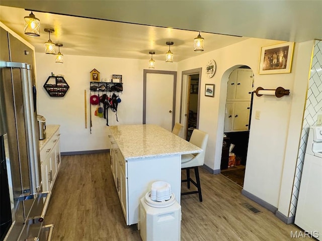 1516 W Main St, Vandalia, IL 62471 - kitchen featuring a breakfast bar, arched walkways, wood finished floors, and a kitchen island