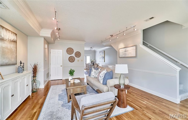 3432 Civic Green Dr, Saint Charles, MO 63301 - living area featuring track lighting, ornamental molding, light wood-style flooring, stairs, and a textured ceiling