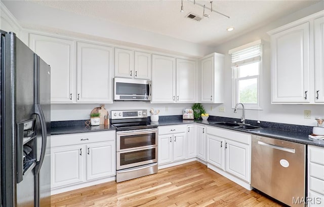 3432 Civic Green Dr, Saint Charles, MO 63301 - kitchen with appliances with stainless steel finishes, dark countertops, white cabinets, light wood-style floors, and recessed lighting