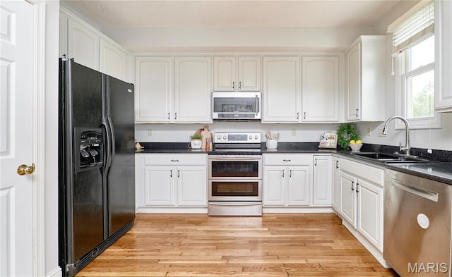 3432 Civic Green Dr, Saint Charles, MO 63301 - kitchen with appliances with stainless steel finishes, white cabinets, dark countertops, and light wood-style flooring
