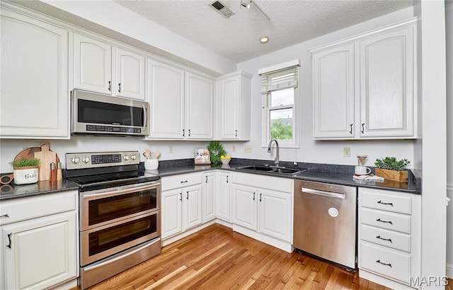 3432 Civic Green Dr, Saint Charles, MO 63301 - kitchen featuring stainless steel appliances, light wood-style flooring, a textured ceiling, and white cabinets