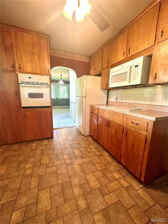 701 Alvarado, Belle, MO 65013 - kitchen featuring white appliances, arched walkways, light countertops, tasteful backsplash, and brown cabinets