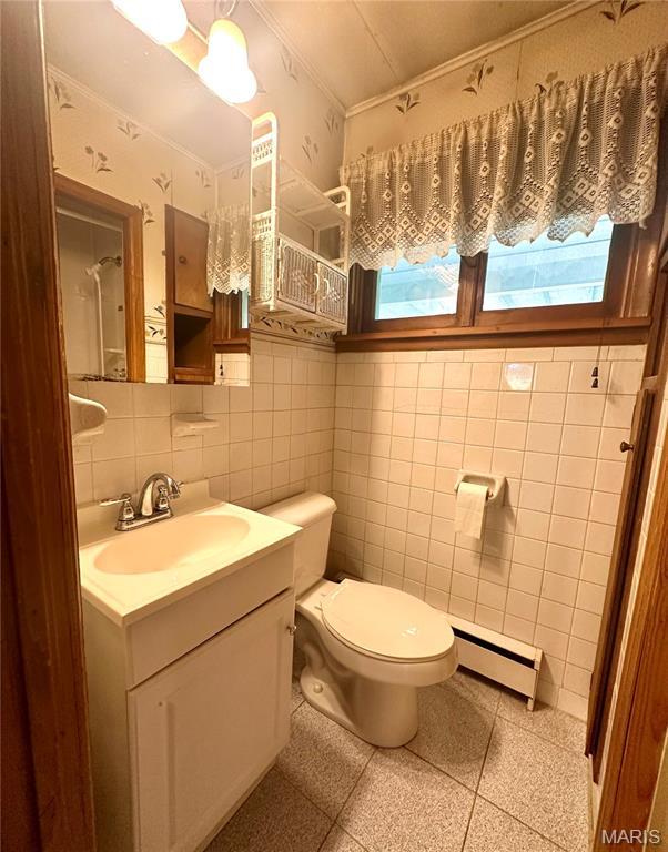 701 Alvarado, Belle, MO 65013 - bathroom with a baseboard heating unit, ornamental molding, vanity, tile walls, and plenty of natural light
