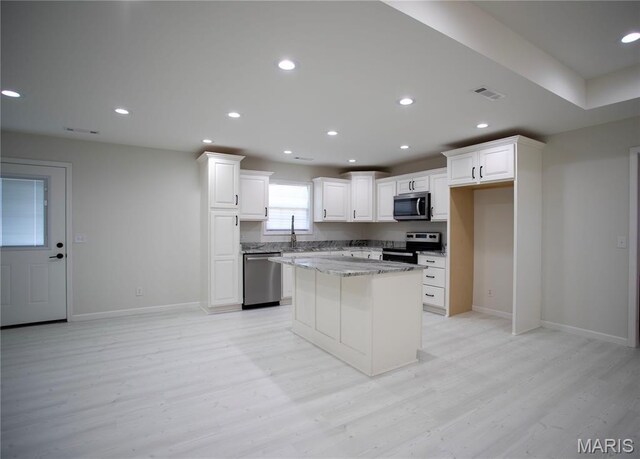 1205 Yosemite, Sikeston, MO 63801 - kitchen featuring appliances with stainless steel finishes, light wood-type flooring, white cabinetry, recessed lighting, and a center island