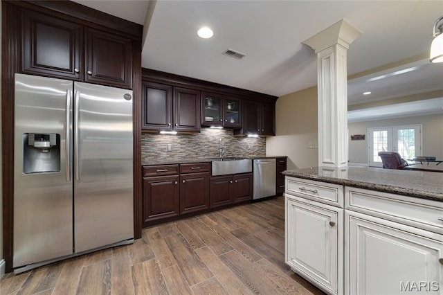 204 Logans Ct, Foristell, MO 63348 - kitchen featuring appliances with stainless steel finishes, ornate columns, dark brown cabinetry, decorative backsplash, and recessed lighting