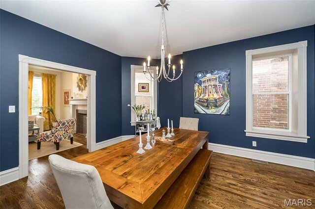 3822 Humphrey St, Saint Louis, MO 63116 - dining space with a chandelier, wood finished floors, and a fireplace
