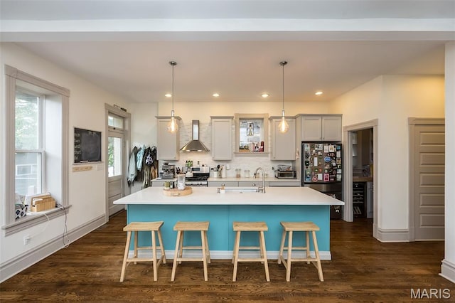 3822 Humphrey St, Saint Louis, MO 63116 - kitchen with freestanding refrigerator, wall chimney exhaust hood, a breakfast bar, a kitchen island with sink, and recessed lighting