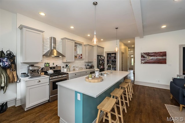 3822 Humphrey St, Saint Louis, MO 63116 - kitchen with wall chimney range hood, stainless steel range with gas cooktop, freestanding refrigerator, a kitchen breakfast bar, and light countertops