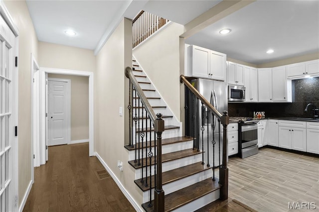 19 N 31st St N, Belleville, IL 62226 - kitchen with appliances with stainless steel finishes, decorative backsplash, wood finished floors, white cabinets, and recessed lighting