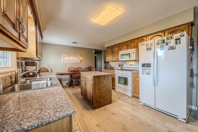 16930 Grace Rd, Lebanon, MO 65536 - kitchen with white appliances, light wood-type flooring, brown cabinetry, a kitchen island, and a textured ceiling