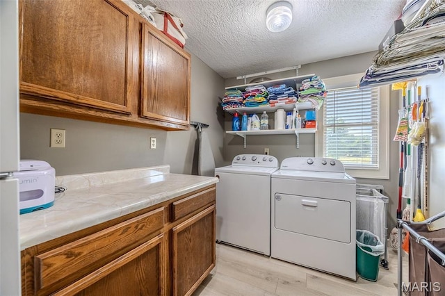 16930 Grace Rd, Lebanon, MO 65536 - washroom featuring washing machine and dryer, cabinet space, a textured ceiling, and light wood-type flooring