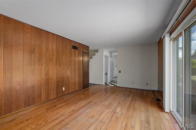7849 Cassia Ct, Saint Louis, MO 63123 - spare room featuring light wood-style flooring, stairway, and wooden walls