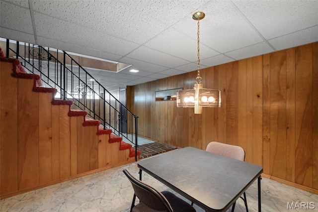 7849 Cassia Ct, Saint Louis, MO 63123 - dining room featuring marble look tiles, a paneled ceiling, stairway, wooden walls, and a chandelier