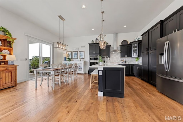 2308 Sand Cherry Dr, Wildwood, MO 63011 - kitchen featuring stainless steel appliances, light countertops, dark cabinets, a kitchen bar, and decorative backsplash