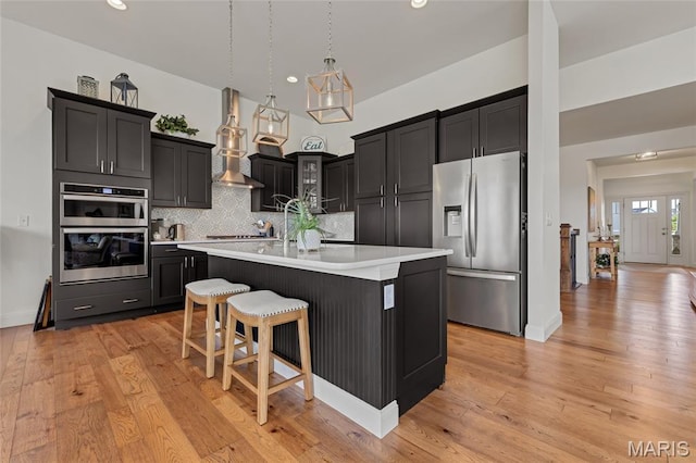 2308 Sand Cherry Dr, Wildwood, MO 63011 - kitchen featuring appliances with stainless steel finishes, light countertops, tasteful backsplash, dark cabinets, and an island with sink