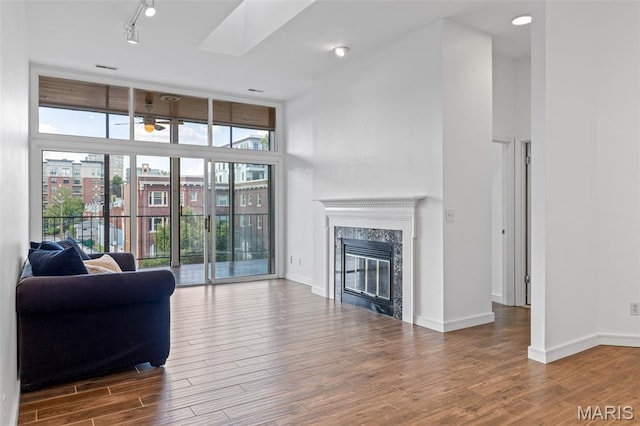 4570 Laclede Ave Unit 301, Saint Louis, MO 63108 - living room featuring wood finished floors, a high end fireplace, ceiling fan, a high ceiling, and a skylight