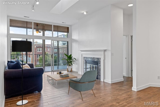 4570 Laclede Ave Unit 301, Saint Louis, MO 63108 - living room with wood finished floors, a premium fireplace, a towering ceiling, ceiling fan, and rail lighting