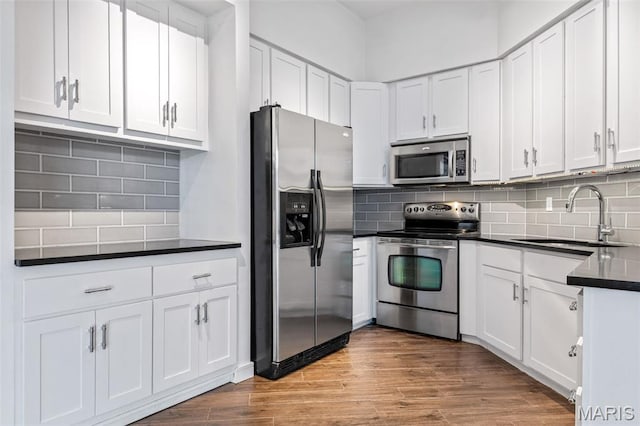 4570 Laclede Ave Unit 301, Saint Louis, MO 63108 - kitchen with appliances with stainless steel finishes, dark countertops, tasteful backsplash, and white cabinets
