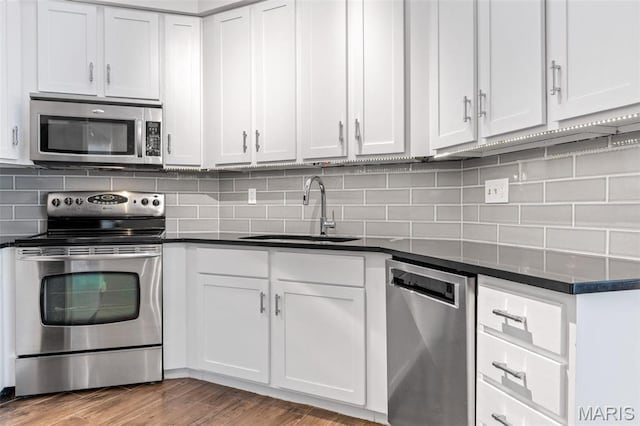 4570 Laclede Ave Unit 301, Saint Louis, MO 63108 - kitchen with appliances with stainless steel finishes, dark countertops, white cabinetry, wood finished floors, and tasteful backsplash