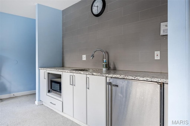 4570 Laclede Ave Unit 301, Saint Louis, MO 63108 - kitchen with refrigerator, decorative backsplash, stainless steel microwave, light stone counters, and white cabinetry