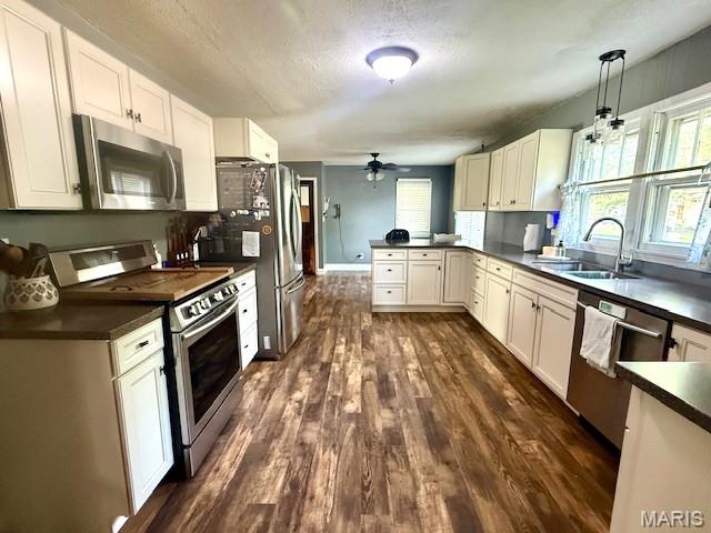 902 Sycamore St, Germantown, IL 62245 - kitchen with stainless steel appliances, dark countertops, a peninsula, dark wood-style floors, and a ceiling fan