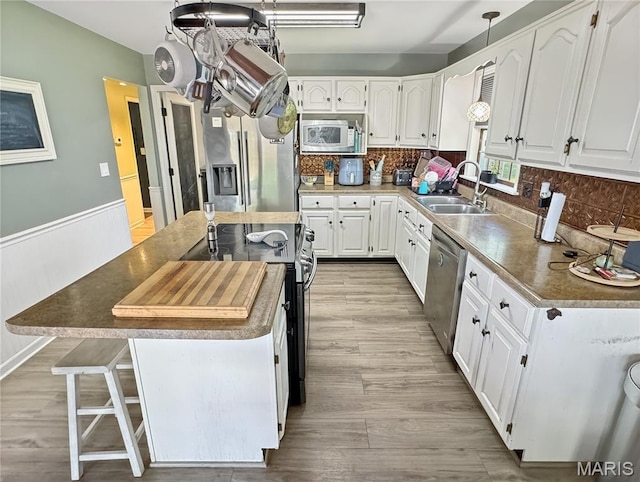 360 David Dr, Washington, MO 63090 - kitchen with stainless steel appliances, a center island, white cabinetry, tasteful backsplash, and a wainscoted wall