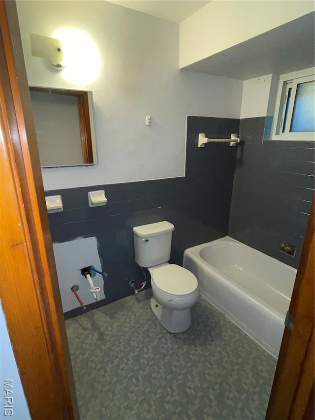 2010-12 E Desoto Ave, Saint Louis, MO 63107 - bathroom featuring tile walls, tile patterned floors, a tub, and a wainscoted wall