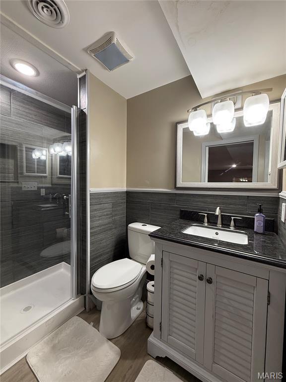 10755 Kennerly Rd, Sunset Hills, MO 63128 - bathroom with tile walls, vanity, a stall shower, wood finished floors, and wainscoting