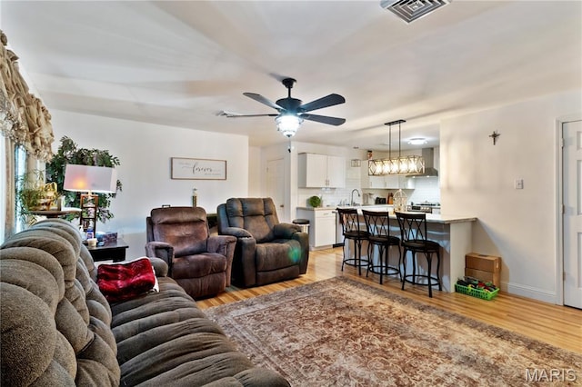 407 N 11th St, De Soto, MO 63020 - living room with light wood-style flooring, ceiling fan, a chandelier, and healthy amount of natural light